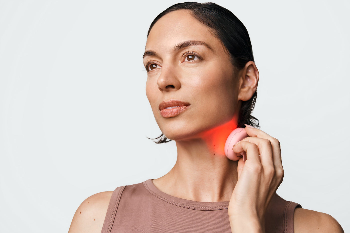 An image of a woman using a red light device on her neck.jpg