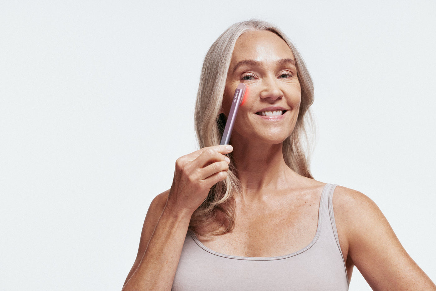 An image of a woman using red light therapy device on her face