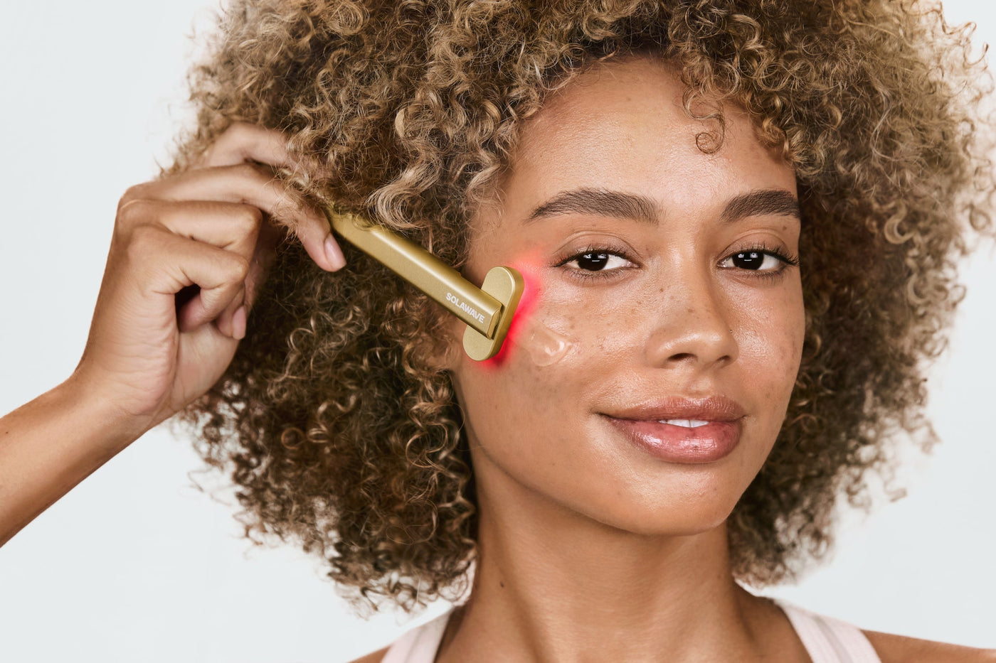 An image of a woman using a red light therapy wand on her face