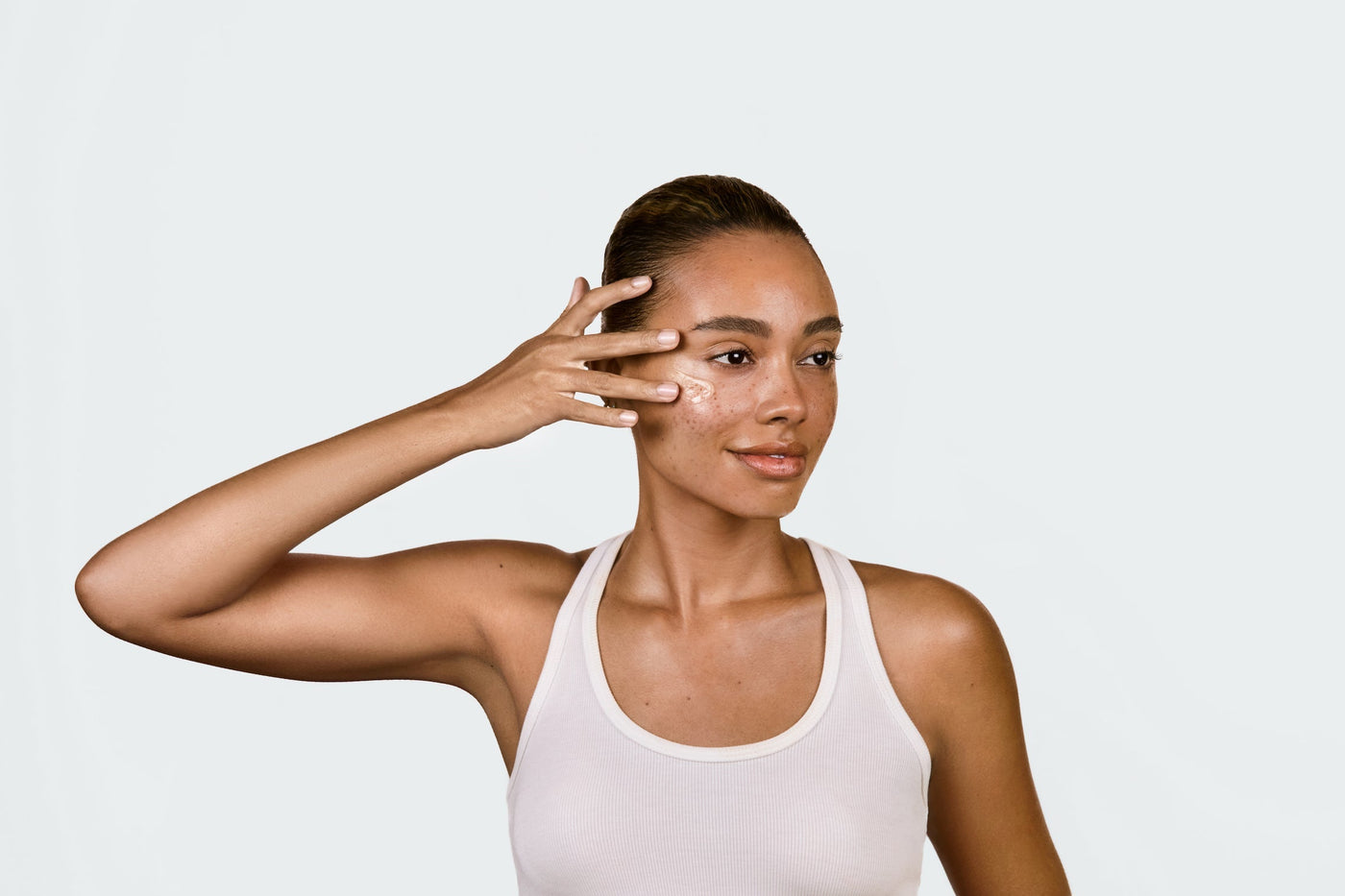 An image of a woman using lightboost serum on her face