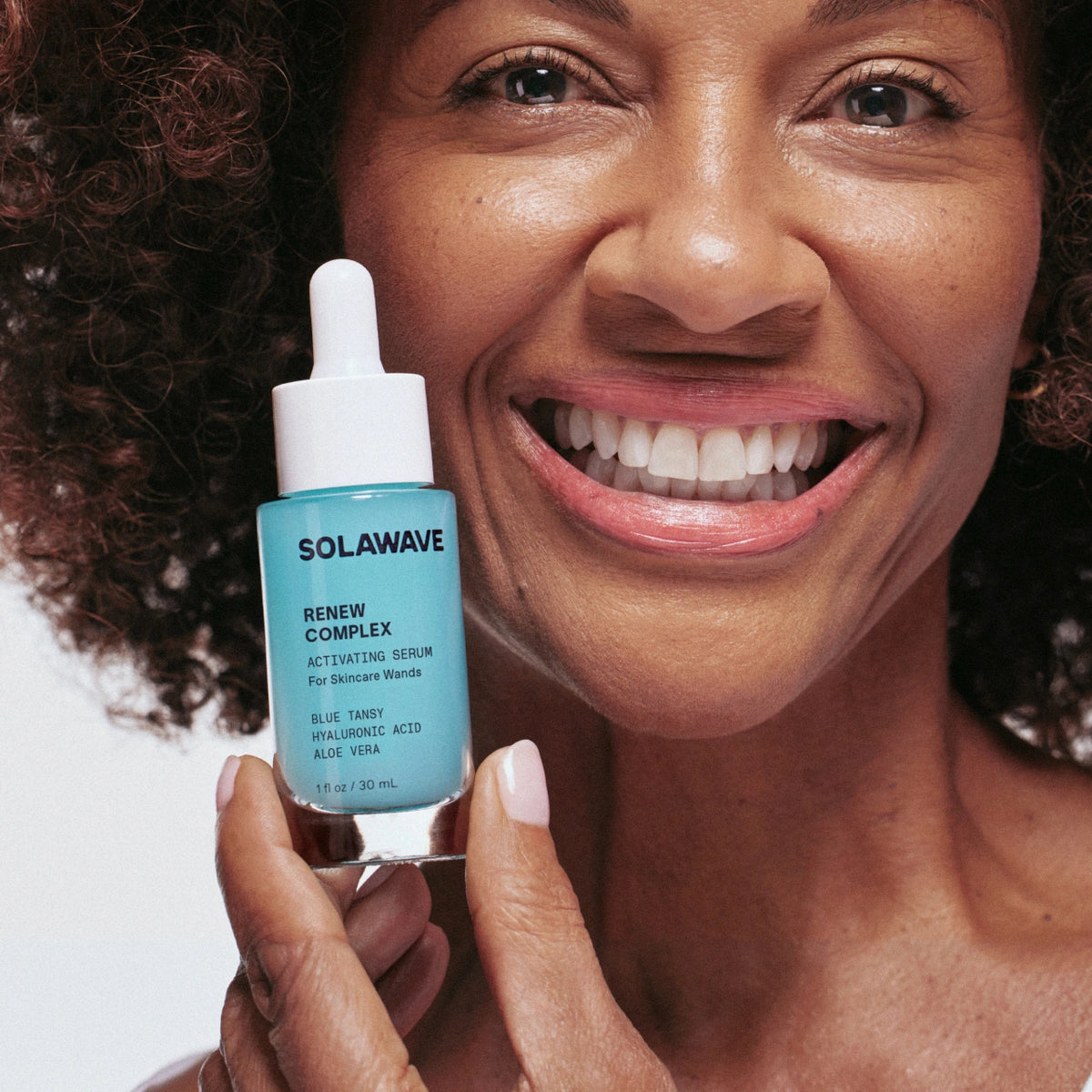 A woman holding up hydrating face serum