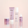 The Solabiome Glowing Skin Starter Kit by SolaWave features four skincare products with probiotics: a moisturizer jar, hydrating gel cleanser tube, jelly mist bottle, and radiance serum dropper. They are presented in chic purple packaging against a soft pink backdrop.