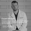 A man in a medical coat sits against a geometric backdrop, with overlay text featuring Daniel Gould, MD, PhDs review of Solawaves 4-in-1 Red Light Therapy Wand & Activating Serum Kit, praising its ease and effectiveness for at-home red light therapy and collagen production. || Charcoal