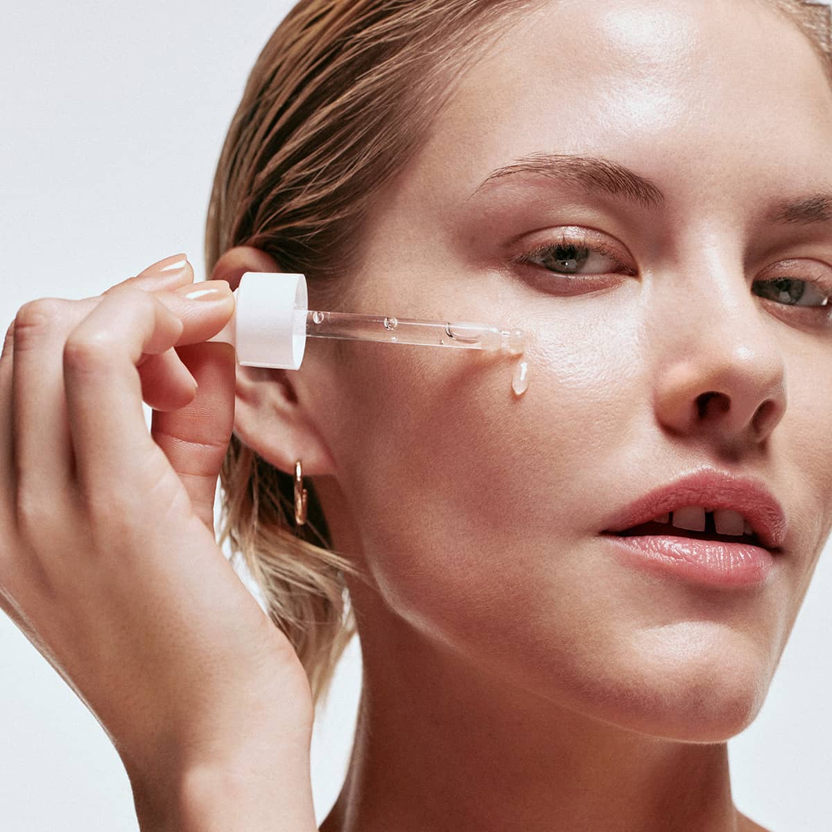 An image of a woman applying hyaluronic face serum