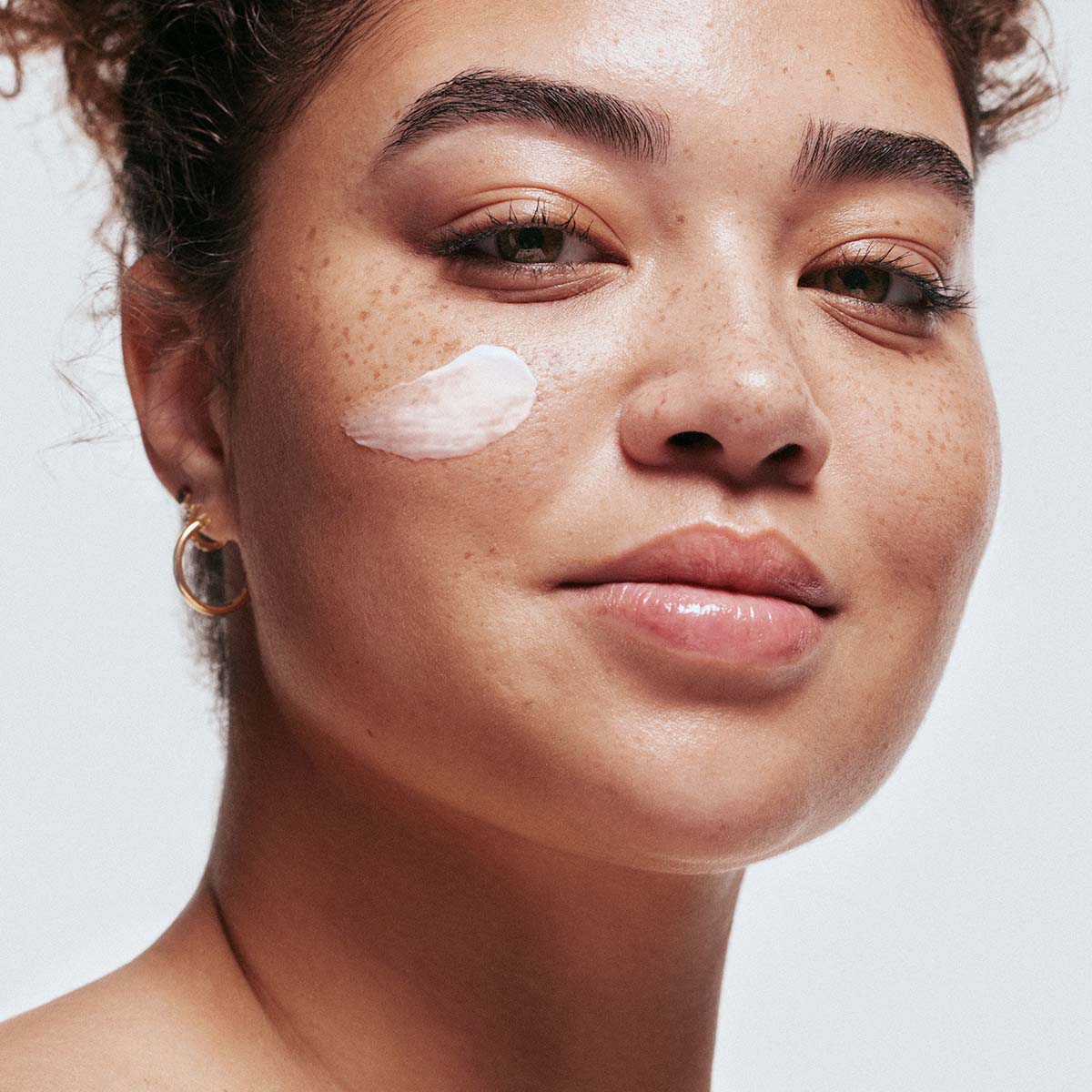 An image of a woman with hydrating skincare products on her face