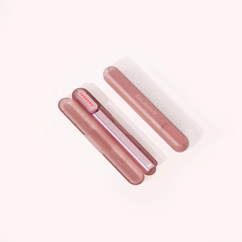 Two pink cylindrical devices, including the Solawave Radiant Renewal Skincare Wand Replacement Carrying Case, are arranged diagonally on a light background. One stands vertically while the other rests horizontally, featuring a sleek design with curved edges and small holes on one end.